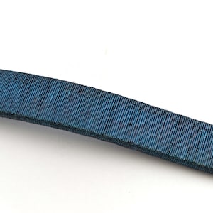 Può includere: Primo piano di un cinturino in tessuto blu.