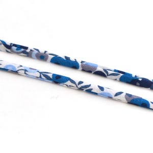 Può includere: Due pezzi di nastro in tessuto con motivo floreale blu e bianco.