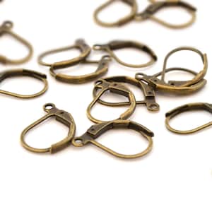 Könnte beinhalten: Eine Gruppe antiker goldfarbener Ohrringhaken. Die Haken sind aus Metall und haben ein schlichtes, klassisches Design.