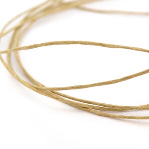 Op de afbeelding: Een close-up van een spoel natuurlijke kleur touw. Het touw is gemaakt van een natuurlijke vezel en is perfect voor knutselen, inpakken en andere doe-het-zelfprojecten.