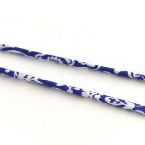Peut inclure: Deux brins de cordon en tissu bleu et blanc à motifs. Le cordon est fin et présente un motif floral.