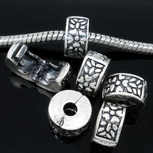 Peut inclure: Six espaceurs de perles en métal argenté avec un motif floral. Les espaceurs sont conçus pour s'adapter à un bracelet à breloques.