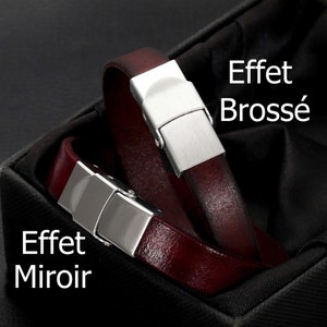 Peut inclure: Deux bracelets en cuir bordeaux avec fermoirs en métal brossé et miroir sont présentés dans une boîte noire. Les bracelets sont en cuir rouge foncé et ont un fermoir rectangulaire en métal.