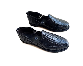 May include: A pair of black leather sandals with a woven design. The sandals have a closed toe and a slip-on style.