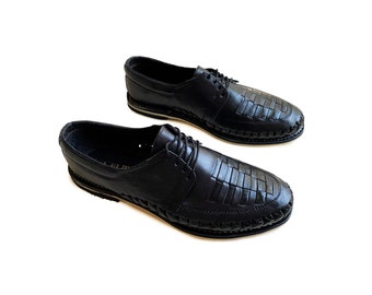 May include: A pair of black leather shoes with a woven design. The shoes have a lace-up closure and a white sole.