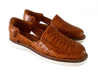 May include: A pair of brown leather sandals with a woven design and white soles. The sandals have a slip-on style and are made of a soft, comfortable leather.