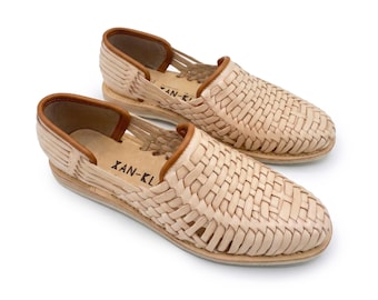 May include: A pair of beige woven leather huarache shoes with a closed toe and open heel design. The shoes feature a tan leather trim along the collar and the brand name XAN-KL printed in black on the inner sole of each shoe.