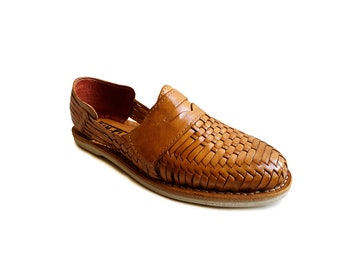 May include: Tan leather sandals with a woven design. The sandals have a slip-on style and a flat sole.