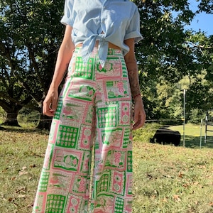 May include: Wide-leg pants with a patchwork design featuring pink, green, and white squares with various patterns. The pants have a high waist and a relaxed fit.