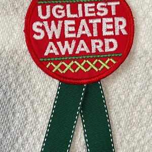 May include: Red and green embroidered patch with the text "Ugliest Sweater Award" and a green ribbon.