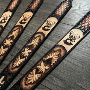 May include: Four leather belts with a deer silhouette design and a woven pattern. The belts are brown and black with a light brown background.
