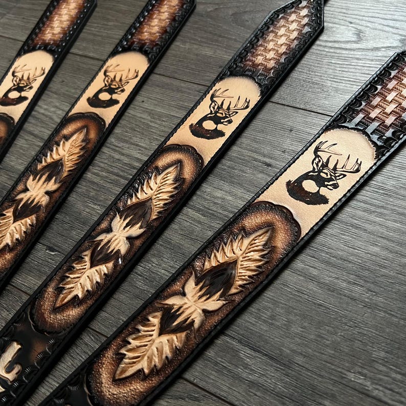 May include: Four leather belts with a deer silhouette design and a woven pattern. The belts are brown and black with a light brown background.