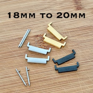 Puede incluir: Varios adaptadores de correas de reloj en dorado, plateado y negro, junto con barras de resorte. El texto "18MM TO 20MM" está visible. Los artículos están dispuestos sobre una superficie de madera.