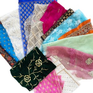 May include: Assortment of fabric scraps in various colors and patterns, including floral, geometric, and lace. The fabrics are arranged in a fan shape, with the most colorful fabrics at the top and the more muted fabrics at the bottom.