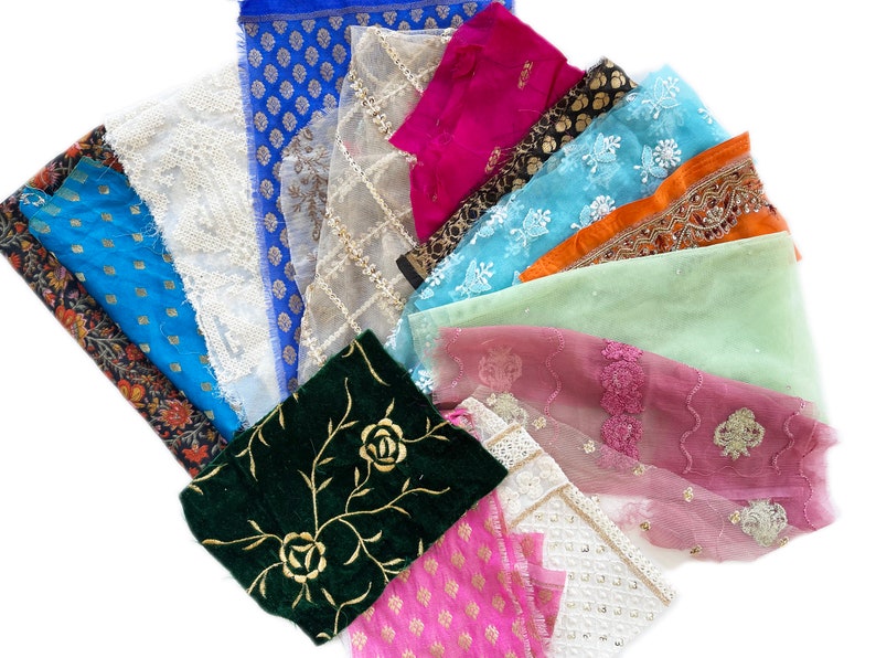 May include: Assortment of fabric scraps in various colors and patterns, including floral, geometric, and lace. The fabrics are arranged in a fan shape, with the most colorful fabrics at the top and the more muted fabrics at the bottom.