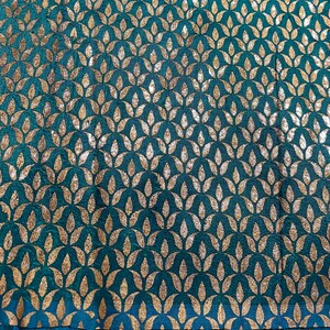 May include: Teal fabric with a repeating pattern of gold leaf-shaped designs.