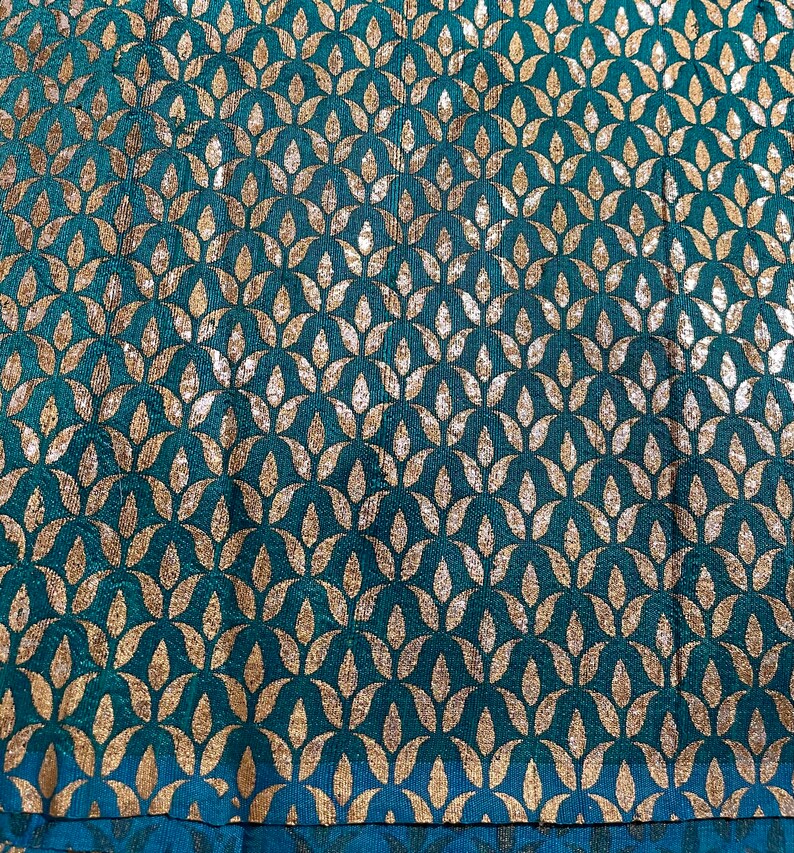 May include: Teal fabric with a repeating pattern of gold leaf-shaped designs.