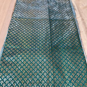 May include: Teal fabric with a gold leaf pattern. The fabric has a subtle sheen and a soft texture.
