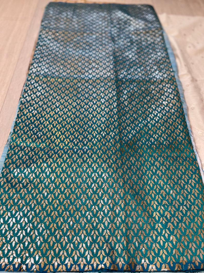 May include: Teal fabric with a gold leaf pattern. The fabric has a subtle sheen and a soft texture.