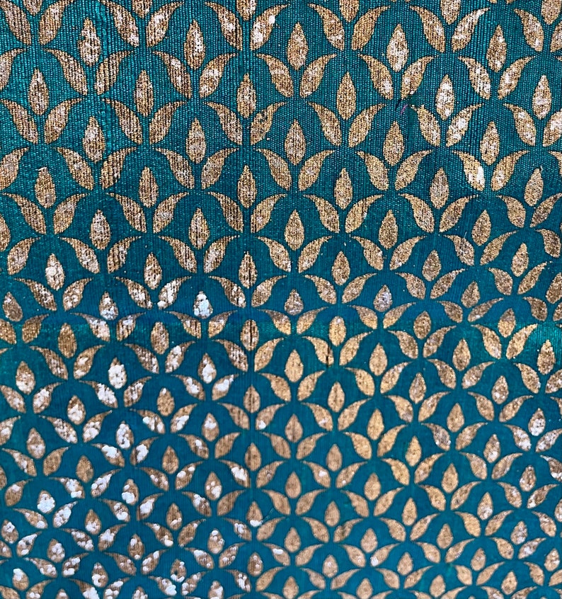 May include: Teal fabric with a gold leaf pattern. The leaves are arranged in a repeating pattern.