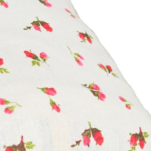 May include: White fabric with a repeating pattern of small pink roses.
