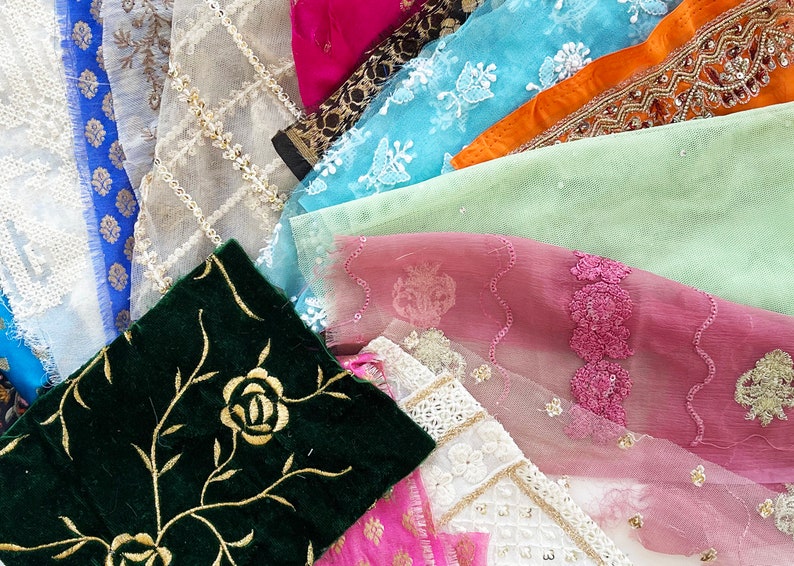 May include: Assortment of fabric swatches in various colors and textures, including lace, velvet, and sheer fabrics. The fabrics feature floral and geometric patterns.