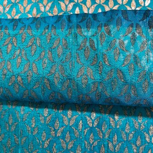 May include: Teal fabric with a silver leaf pattern. The fabric is folded in half, showing the pattern on both sides.
