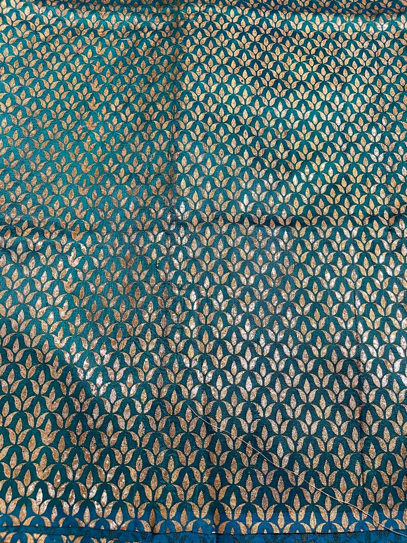 May include: Teal fabric with a repeating pattern of gold leaf stylized floral motifs.
