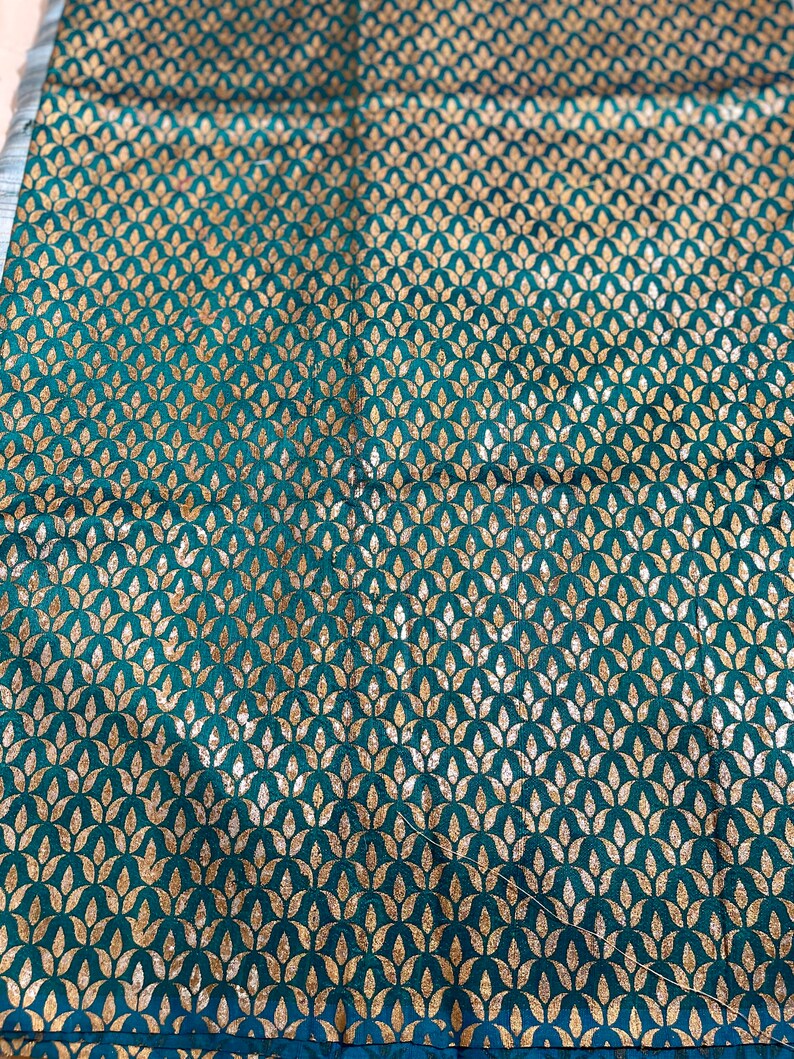 May include: Teal fabric with a repeating pattern of gold leaf stylized floral motifs.