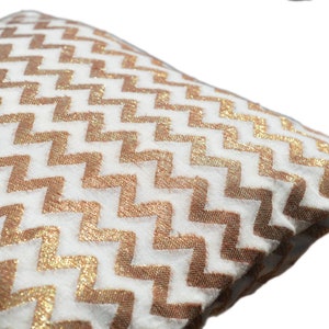May include: White throw pillow with a gold chevron pattern.