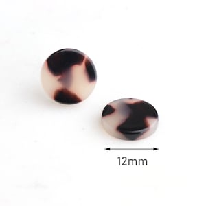 May include: A pair of round, black and white patterned earrings. The earrings are 12mm in diameter.