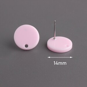 May include: A pair of pink round stud earrings with a silver post. The earrings are 14 mm in diameter.