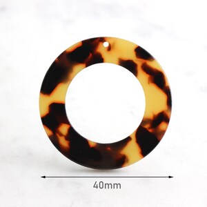 May include: A round, tortoiseshell-patterned pendant with a hole at the top. The pendant measures 40mm in diameter.