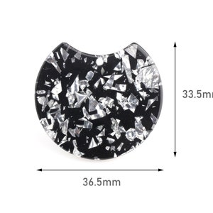 May include: A black and silver round pendant with a curved top edge. The pendant is 36.5mm wide and 33.5mm tall. It is filled with silver glitter-like pieces. A small hole is at the top for stringing.