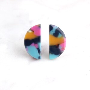 May include: A pair of colorful half-circle earrings with a marbled pattern in shades of blue, pink, yellow, and black.