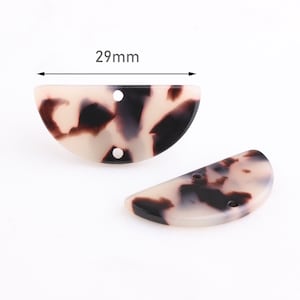 Può includere: Due perline di plastica a forma di semicerchio con un motivo a tartaruga. Le perline sono larghe 29 mm e hanno due fori.