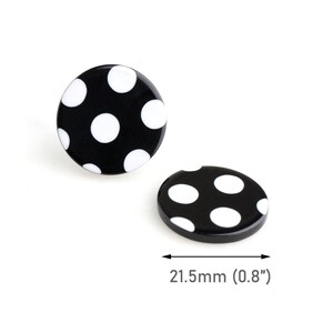 Peut inclure: Deux boutons noirs et blancs à pois. Les boutons sont de forme ronde et ovale, avec des pois blancs sur fond noir. Le plus grand bouton mesure 21,5 mm de diamètre.