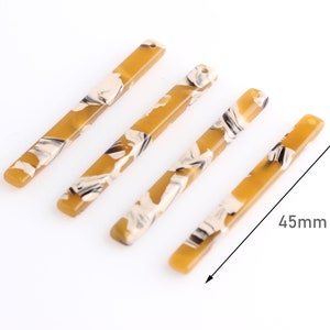 Könnte beinhalten: Vier braune und weiße marmorierte rechteckige Acryl-Haarbänder, jedes 11,4 cm lang.