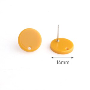 May include: Mustard yellow stud earrings. Each earring is a flat, circular disc with a post for piercing. The earrings are 14mm in diameter. The earrings are set against a white background.