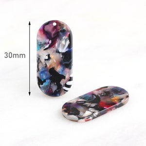 Könnte beinhalten: Zwei ovale, farbige Anhänger aus Harz mit einem marmorierten, abstrakten Design. Die Anhänger sind etwa 30 mm lang.