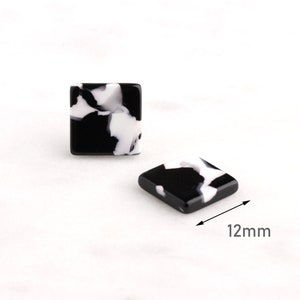 May include: A pair of black and white square earrings with a marbled pattern. Each earring measures 12mm in size.