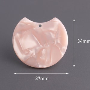 May include: A pink, marbled, half-circle shaped pendant with a hole at the top. The pendant measures 37 mm wide and 34 mm high.