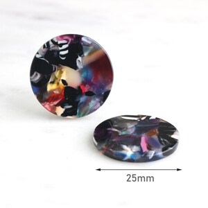 May include: Two round, colorful, abstract resin earrings. Each earring is 25mm in diameter and features a swirling pattern of black, white, red, yellow, blue, and purple.