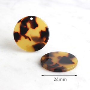 May include: Two round, tortoise shell-patterned acrylic pendants. One pendant has a hole drilled at the top. The other pendant is flat. The diameter of the pendants is 24mm.
