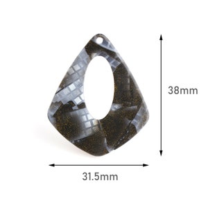 May include: Black and white geometric patterned resin earring with a gold glitter finish. The earring is 38mm tall and 31.5mm wide.