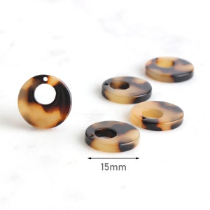 Könnte beinhalten: Fünf runde, flache, dekorative Kunststoffstücke in Braun und Creme mit einem Loch in der Mitte. Die Stücke haben einen Durchmesser von 15 mm.