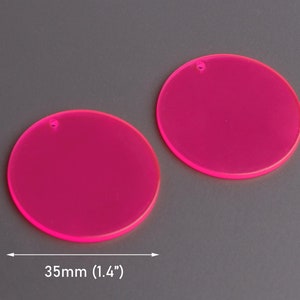 May include: Two bright pink, round acrylic blanks with a hole in the center. Each blank measures 1.4 inches in diameter.