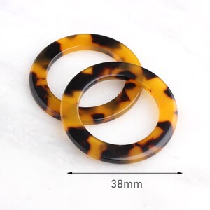 May include: Two brown and black tortoiseshell plastic rings, each with a diameter of 38mm.