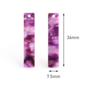 Könnte beinhalten: Zwei rechteckige Anhänger aus marmoriertem Acryl in Lila und Weiß mit einem Loch oben. Die Anhänger sind 36 mm lang und 7,5 mm breit.