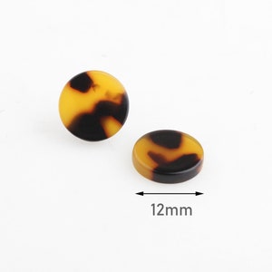 May include: Two round, brown and yellow tortoise shell earrings, each measuring 12 mm in diameter.